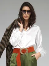 Camisa color beige de raso con cuello clásico, cierre frontal con botones y mangas largas con puños adornados con plumas.