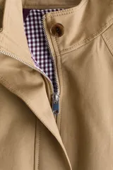 Campera oversized de sarga de algodón color beige, con cuello elevado, cierre frontal oculto y solapa rompevientos. Cuenta con mangas raglán, bolsillos delanteros con solapa y botón, y cordón ajustable en el bajo que frunce la cintura.