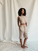 Camiseta corta color beige, sin mangas y con cuello camisero.