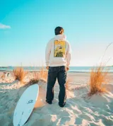 Hoodie de corte oversize en color natural, con capucha y un gran estampado en la espalda con la inscripción "Glassy Waves" sobre un fondo amarillo.