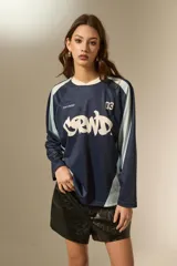 Remera de manga larga estilo deportivo, confeccionada en tejido técnico. Presenta un diseño color block en tonos bordó y rosa, con cuello mao y estampado gráfico frontal en color blanco.