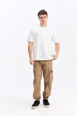 Pantalón cargo color tostado de corte amplio, con cintura elástica y cordón ajustable. Cuenta con bolsillos laterales con tapa en las piernas y puños elastizados en los tobillos.