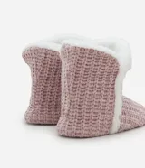 Pantufla tipo bota en color rosado, con superficie externa de tejido texturizado y borde superior e interior forrado en peluche blanco.