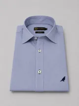 Camisa de algodón color celeste, corte slim fit, con cuello clásico, botones blancos con costura azul y un bordado de un pájaro en el pecho.