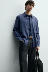 Camisa de corte regular fit en color azul, confeccionada en mezcla de lyocell y algodón, con cuello camisero, manga larga con puños abotonados, cierre frontal con botones y un bolsillo aplicado en el pecho.