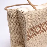 Bolso tipo shopper de yute color beige con diseño geométrico marrón en el centro. Asas cortas de soga.