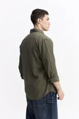 Camisa de manga larga color azul marino con textura, cuenta con cuello clásico, cierre frontal con botones y un bolsillo en el pecho.