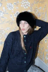 Saco tejido de punto con diseño de ochos y trenzas, color azul marino. Presenta cierre frontal con botones en contraste de color turquesa y un delicado bordado a mano en el pecho.