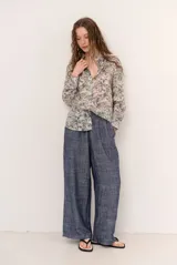 Camisa de manga larga con estampado de hojas en tonos azules y beige, cierre frontal con botones y cuello camisero clásico.