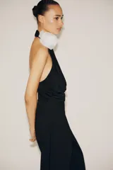 Body negro de cuello halter con escote drapeado pronunciado, detalle de flor blanca en relieve y espalda descubierta.