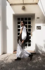 Bolso tipo hobo de gran tamaño en color marrón, confeccionado en gamuza. Presenta un diseño con flecos largos en la parte inferior, cierre superior y una correa trenzada con detalles artesanales.