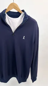 Buzo azul marino de algodón de punto con medio cierre y cuello alto. Presenta un logo pequeño bordado en el pecho.