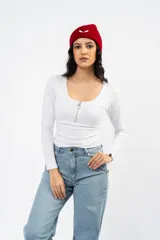 Remera de manga larga color blanco, confeccionada en algodón con lycra, con escote redondo y cierre frontal metálico.
