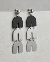 Caravanas colgantes de acero italiano, compuestas por tres piezas articuladas en forma de arco, con acabado bicolor en negro y plateado.