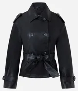 Campera de cuero sintético estilo trench, con cuello solapa, cierre frontal de botones y lazo ajustable en la cintura. Presenta detalles utilitarios en hombros y puños.