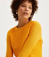 Blusa de punto color celeste con textura ondulada, cuello redondo y mangas largas.