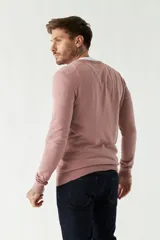 Sweater de punto color rosa con cuello en V y logo bordado en el pecho.