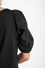 Remera negra de algodón con cuello redondo y mangas globo cortas confeccionadas en tela con detalle de broderie.