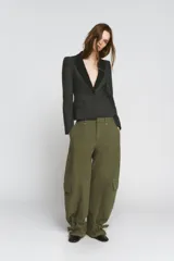 Pantalón cargo de tiro medio confeccionado en algodón, con diseño de pierna ancha y costuras verticales. Presenta bolsillos laterales y bolsillos de plastrón con solapa en las piernas. El bajo es ajustable mediante trabillas y hebillas metálicas.