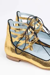 Botines dorados con estampado de escamas, con cordones negros y detalles calados.
