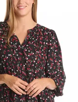 Blusa de gasa con estampado de corazones rojos y blancos sobre fondo negro. Presenta cuello redondo con escote en V, mangas largas con puños fruncidos y un corte holgado con detalle de frunces en la cintura.