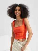 Top corto de color rojo con escote cuadrado, tirantes anchos y un pequeño lazo decorativo en el centro del pecho.