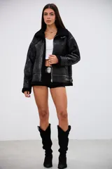 Campera tipo gamulán de corte oversize, confeccionada en cuero sintético con acabado texturizado y forro interior de corderito sintético negro. Presenta cierre frontal, cuello con solapas, detalles de tiras con hebilla en el ruedo y terminaciones en corderito en puños y bordes.