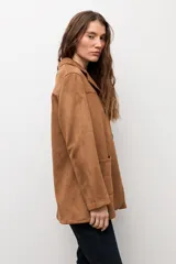 Blazer de gamuza sintética color camel, con cierre frontal de tres botones, solapas clásicas y dos bolsillos frontales de parche.