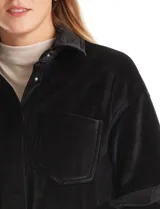 Sobrecamisa de pana con textura acanalada, corte oversize y silueta holgada. Presenta cuello clásico, cierre frontal con botones metálicos, mangas largas con puños abotonados y dos bolsillos frontales tipo parche con solapa.