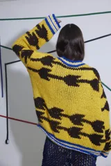 Sweater tejido a mano en lana color amarillo con diseño abstracto en marrón y detalles en azul en cuello y puños. De calce holgado, cuello a la base y puños ajustados.