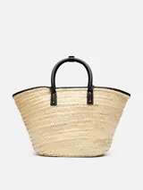 Bolso tipo canasto Jacquemus Le Panier Soli tejido en fibra vegetal de color natural, con asas cortas, detalles y bolsillo frontal de cuero negro con el logotipo de la marca en letras doradas.