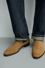 Bota estilo Chelsea fabricada en piel con acabado de serraje, cuenta con elásticos laterales para facilitar el calce, horma redonda y suela a contraste con un ligero tacón.