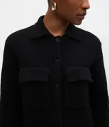 Campera de punto con textura, corte recto y cuello clásico. Presenta cierre frontal con botones y dos bolsillos aplicados con solapa en el pecho.