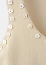 Top de punto fino color beige con tirantes anchos, escote redondo y detalle de perlas aplicadas a lo largo del borde del escote.