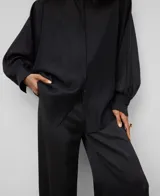 Camisa amplia semitransparente color blanco, con cuello chimenea y manga japonesa con puño. Presenta botonadura frontal oculta por solapa.