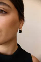 Aros de acero quirúrgico dorado con dije colgante en forma de argolla de piedra natural negra con destellos.