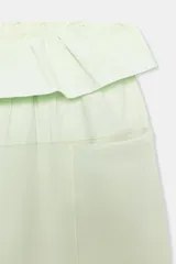 Pantalón verde claro de tiro medio, con bolsillos delanteros y cintura ajustable con cordones y volantes del mismo tejido.