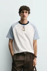 Camiseta de hombre regular fit, color blanco con mangas raglán cortas en azul claro y cuello redondo en rib azul marino.
