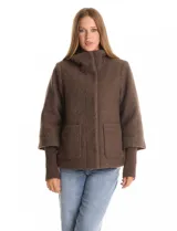 Tapado de tejido bouclé color marrón, con silueta evasé y largo a la cadera. Presenta cuello alto envolvente, cierre frontal oculto con botones a presión y bolsillos frontales de gran tamaño. Sus mangas son 3/4 con corte amplio y puños de tejido rib al tono que se extienden para cubrir las muñecas.