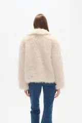 Campera de piel sintética color negro, con cuello, manga larga y cierre frontal. Presenta un diseño de corte holgado y textura suave.