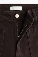 Pantalón jean de tiro alto en color marrón, de corte amplio y relajado, con bolsillos delanteros de parche y raya marcada al frente.