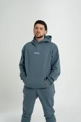 Conjunto deportivo gris compuesto por un hoodie con capucha, bolsillo canguro y logo estampado en el pecho, y un pantalón jogging con cintura elástica y cordón ajustable.
