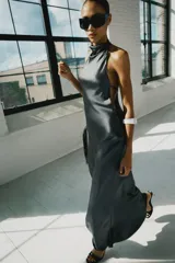 Vestido largo satinado color gris oscuro, con cuello halter, hombros descubiertos y cierre en la espalda con cremallera oculta.
