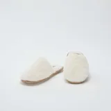 Pantuflas abiertas de pelo sintético color beige con suela marrón.