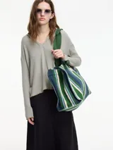 Buzo de tejido de punto gris claro, con cuello tipo polo y escote en V. Presenta manga larga y pespuntes a contratono en los bordes.