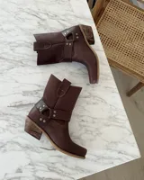 Bota estilo tejana de cuero vacuno color bordó, con detalle de argolla metálica y remaches decorativos.