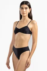 Conjunto de bikini negro con textura brillante, compuesto por un corpiño de corte triangular con breteles finos y una bombacha de tiro alto.