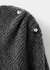 Jersey de punto medio color gris, con diseño recto, cuello barco, manga larga y bajo asimétrico. Cuenta con detalle metálico en el hombro.