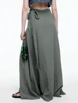 Falda larga color beige, de corte evasé y tiro alto, con lazo ajustable en la cintura.