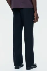 Pantalón negro de corte regular, confeccionado en una mezcla vaporosa de lino y algodón. Presenta cintura con elástico revestido y cordón de ajuste, cierre con botón y bragueta, bolsillos laterales y bolsillos traseros insertados.